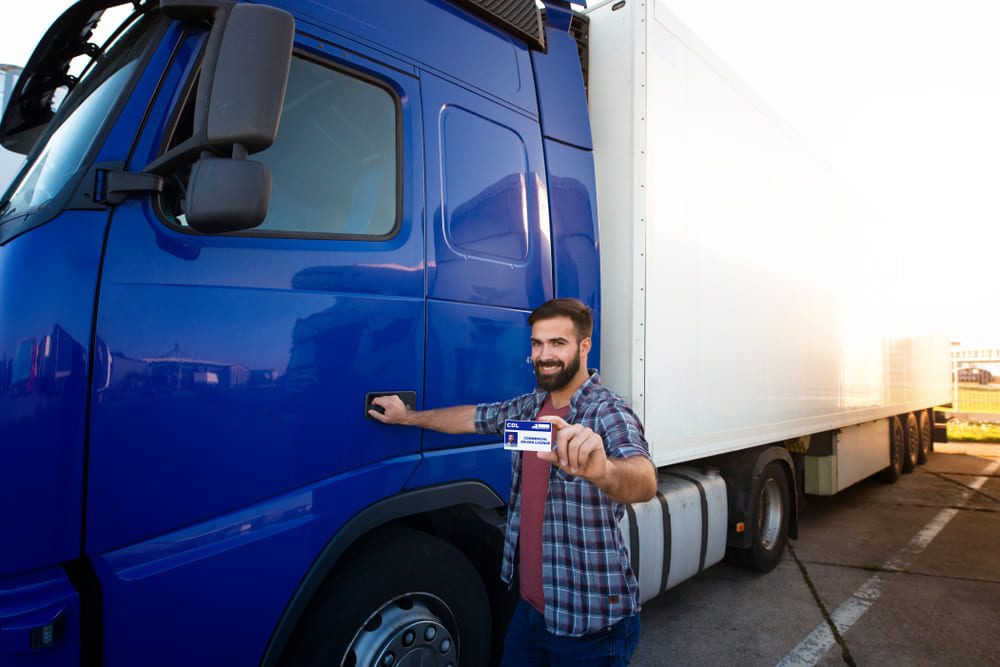 the driver is displaying his id card standing next to an enclosed truck.